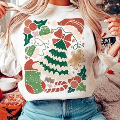 a woman sitting on the floor wearing a christmas sweater and holding her hair in one hand