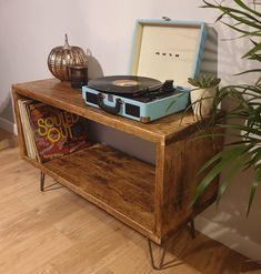 a record player sitting on top of a wooden table next to a potted plant