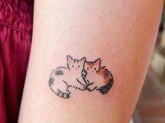 a woman with a cat tattoo on her arm is holding onto another cat's tail