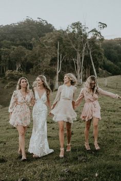 three bridesmaids walking in the grass holding hands