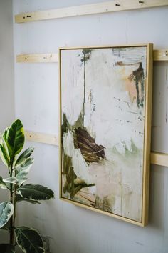 a painting hanging on the wall next to a potted plant