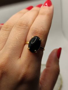 Gift sophistication and strength with our Onyx Ring. This exquisite piece, featuring the timeless beauty of black onyx, make a perfect gift for any occasion. Share the elegance and boldness of this gemstone with someone special, and make their day truly memorable. 🔸Adjustable band 🔸12mm stone size 🔸Color back 🔸Gold filled We offer  🔸Fast shipping ( under normal conditions) 🔸Free shipping  🔸Polishing cloth ( to keep your piece shiny) 🔸Jewelry case on orders of 100€ 🔸Gift box 🎁 🔸Great customer service                                 Onyx, with its deep black elegance, symbolizes strength and protection. Its sleek beauty has made it a prized gemstone in jewelry and decorative arts for centuries. Whether for aesthetics or its grounding properties, onyx is a timeless and captivating Classic Black Oval Cabochon Ring, Formal Onyx Open Ring, Onyx Gemstone Ring Jewelry, Classic Black Jewelry With Round Stone, Black Enamel Onyx Round Rings, Black Oval Sapphire Promise Ring, Classic Black Oval Sapphire Ring, Classic Black Sapphire Oval Ring, Onyx Gemstone Ring As Gift