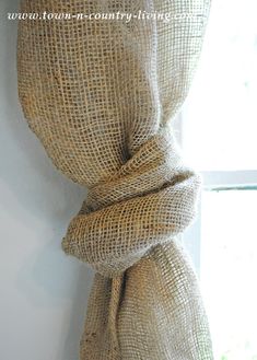 a burlap curtain hanging on the side of a window