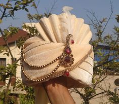 a woman holding up a white hat with jewels on it