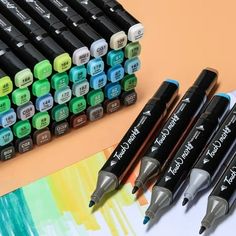 several markers and pens sitting next to each other on top of a paper with watercolors