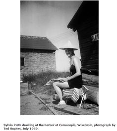 a black and white photo of a woman in a hat sitting on the curb next to a building