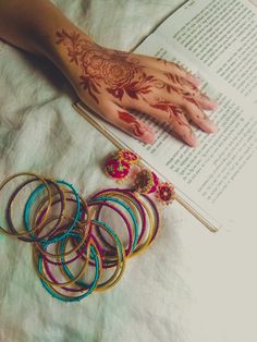 henna tattoos and bracelets on a bed next to an open book