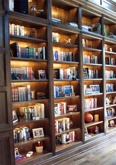 a bookshelf filled with lots of books on top of wooden shelves in a room