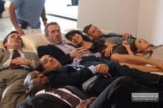 a group of men laying on top of each other in suits and ties, all looking up