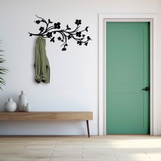 a green door in a white room with a bench and coat rack on the wall