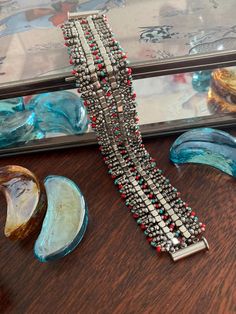 the beaded bracelet is sitting on top of a table next to other glass items