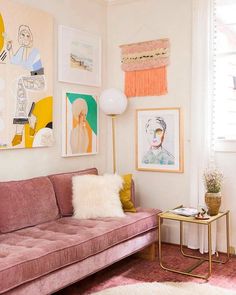 a living room with pink couches and pictures on the wall above them, along with a rug