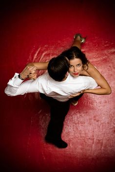 a man and woman posing for a photo in front of a red background with their arms around each other