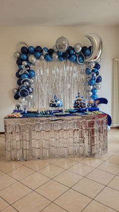 a table topped with blue and silver balloons on top of a tiled floor next to a wall