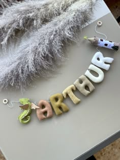 the letters are made out of felt and placed on top of a table with feathers