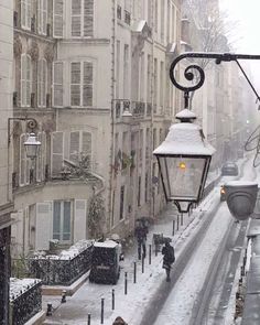 a street light is covered in snow as people walk on the sidewalk