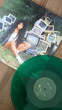 a green vinyl record sitting on top of a wooden table next to a magazine cover