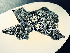 an intricately designed piece of paper sitting on top of a white plate with black ink