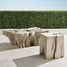 two pieces of wood sitting on top of a cement floor next to a green hedge