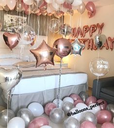 balloons and heliums are floating in the air near a bed with a happy birthday sign on it