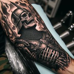 a man's arm with a black and grey tattoo on it, featuring a skeleton wearing a helmet