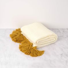 two yellow and white blankets laying on top of a marble counter next to each other