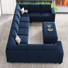 a blue sectional couch sitting on top of a rug in front of a large window