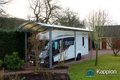 a white motor home parked in front of a green hedge and tree lined driveway area