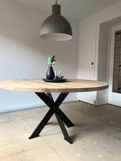 a wooden table with two black vases on it and a light hanging from the ceiling