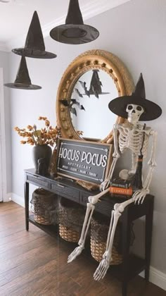 halloween decorations with skeletons and witches in front of a mirror on the wall above a table