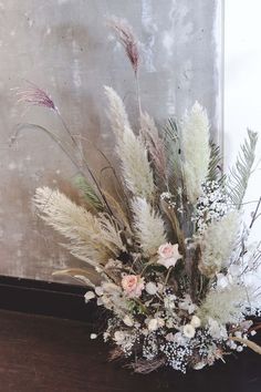 a vase filled with lots of flowers on top of a wooden table next to a wall