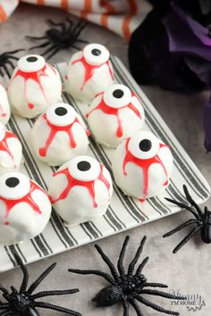 white and red decorated cookies on a plate with black spider webs around the edges