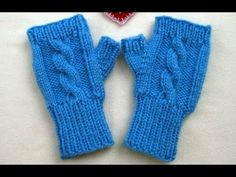 two blue knitted mittens next to a small red heart on a white surface