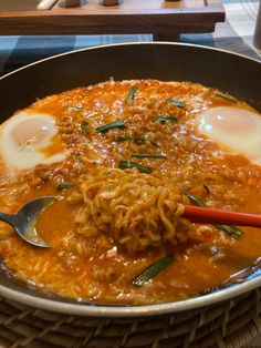 a bowl filled with noodles and eggs on top of a table