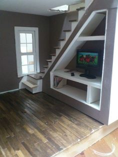 a living room with stairs and a tv in the corner on top of a wooden floor