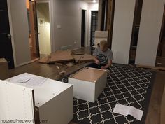 a young boy sitting on the floor in an empty room with boxes scattered around him