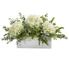 a white vase filled with flowers and greenery