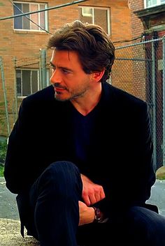 a man sitting on the ground next to a skateboard in front of a building