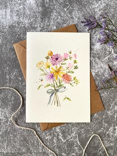 a card with watercolor flowers on it next to a string and some lavenders