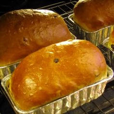 three loafs of bread sitting in tins on an oven rack, ready to be baked