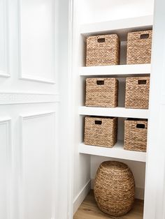 a white closet with wicker baskets on the bottom shelf and wooden flooring underneath