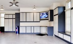 an empty garage with blue and white cabinetry on the walls, windows, and ceiling fan