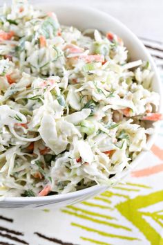 a white bowl filled with coleslaw salad on top of a colorful table cloth