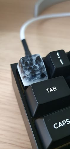 a close up of a computer keyboard on a wooden table with cable plugged into it