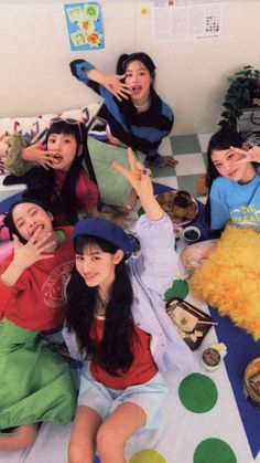 a group of young women sitting on top of a bed next to each other with their hands in the air