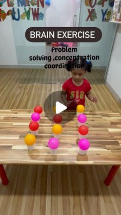 a little boy playing with some balls on a wooden table in the middle of a room