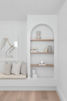 a living room with white walls and shelves filled with vases on top of them