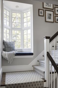 a white staircase leading up to a window with pictures on the wall and below it