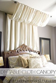 a bed with white sheets and pillows in front of a window covered by drapes