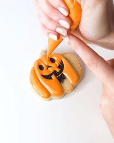 a person is decorating some cookies with icing and pumpkins on them for halloween